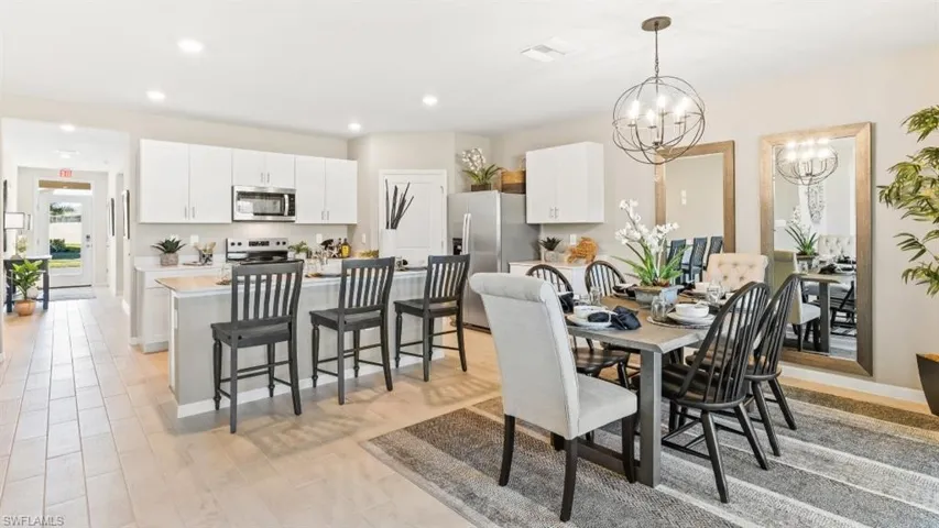 Model Home. The kitchen features white cabinetry, stainless steel appliances, and a breakfast bar with seating