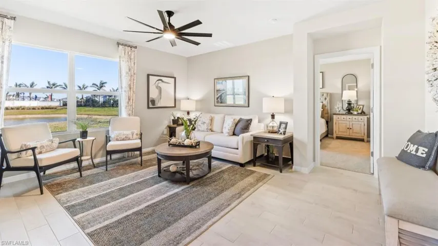 Model Home. Spacious living area featuring large windows, a ceiling fan, and light-colored tile flooring