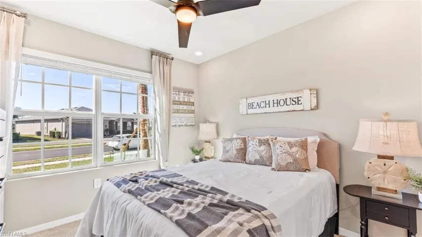 Model Home. This room features a ceiling fan, a large window with white blinds and drapes, and neutral colored walls