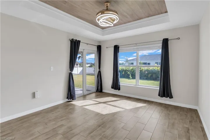 Empty room featuring light wood-type flooring, a raised ceiling, wood ceiling, and plenty of natural light