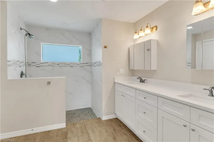 Bathroom featuring wood-type flooring, vanity, and a tile shower