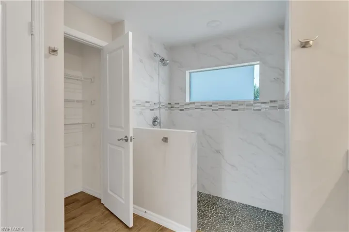 Bathroom with hardwood / wood-style flooring and tiled shower