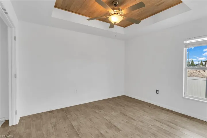 Spare room featuring light wood-type flooring, a raised ceiling, and wooden ceiling