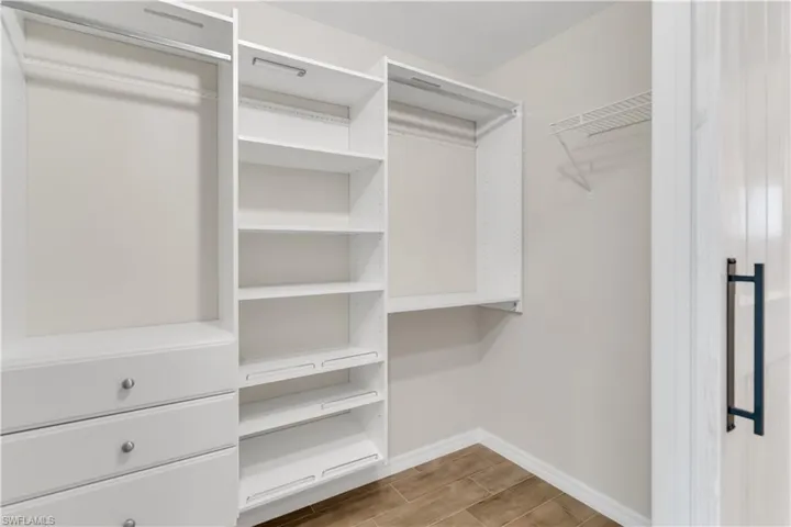 Walk in closet with hardwood / wood-style flooring