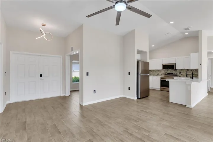 Kitchen with light hardwood / wood-style floors, white cabinets, backsplash, appliances with stainless steel finishes, and ceiling fan