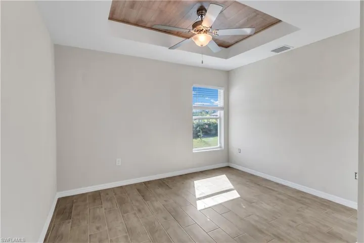 Unfurnished room with light wood-type flooring, a tray ceiling, ceiling fan, and wooden ceiling