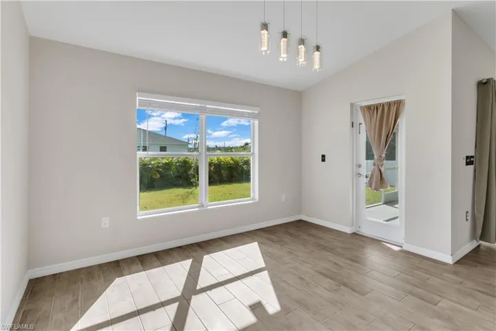 Unfurnished dining area featuring light wood-type flooring, a healthy amount of sunlight, and lofted ceiling