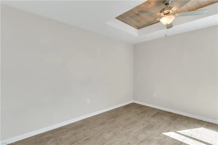 Unfurnished room with light hardwood / wood-style floors, a raised ceiling, wooden ceiling, and ceiling fan