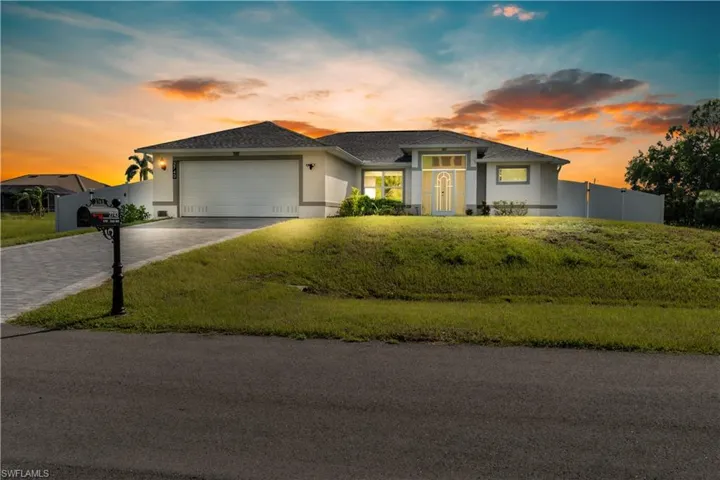 View of front of property featuring a garage and a lawn