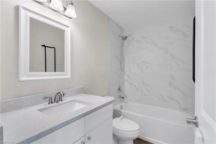 Full bathroom featuring tiled shower / bath combo, vanity, and toilet