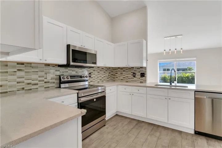 Kitchen with appliances with stainless steel finishes, light wood-type flooring, white cabinetry, and sink