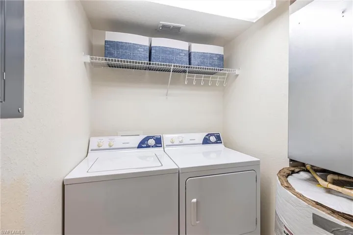 Washroom with washer and clothes dryer, electric panel, and a textured wall
