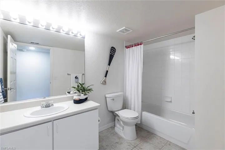 Bathroom featuring tile patterned floors, vanity, shower / tub combo, a textured ceiling, and a textured wall