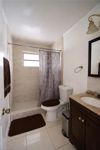 Bathroom with a stall shower, vanity, crown molding, and light tile patterned floors
