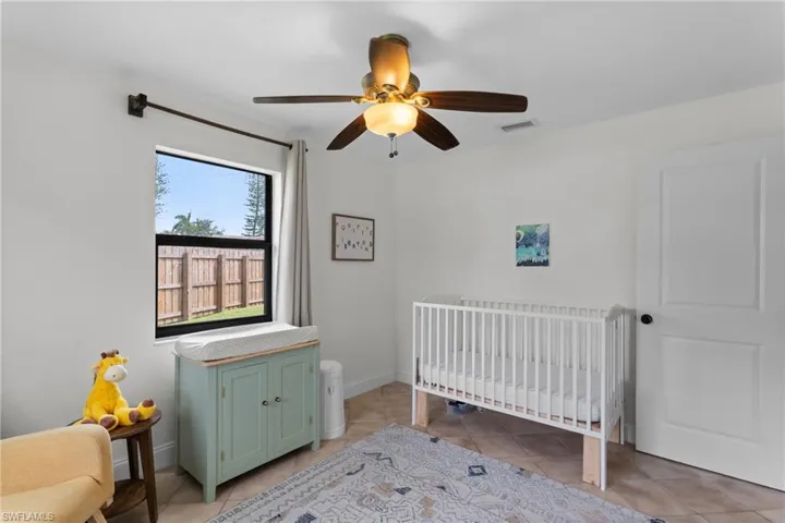 Bedroom featuring ceiling fan, light tile patterned flooring, and a nursery area