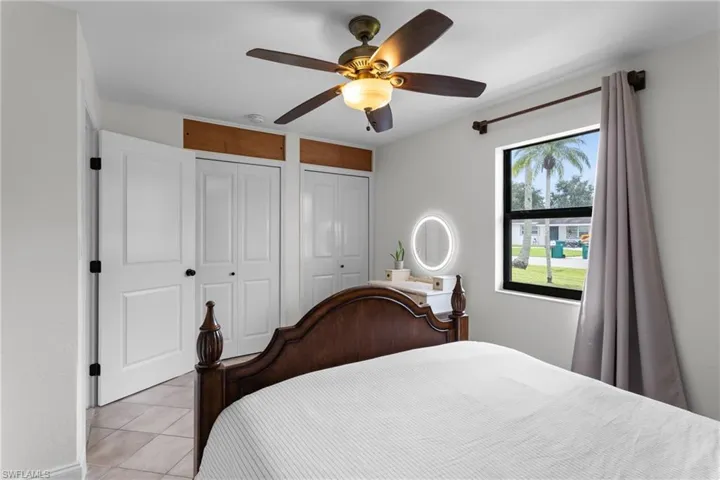 Tiled bedroom featuring ceiling fan and two closets