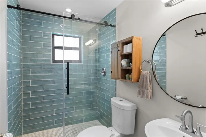 Bathroom with a shower with door, toilet, and sink
