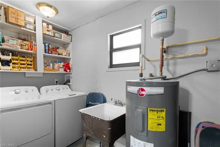 Laundry room featuring water heater, sink, and washing machine and dryer