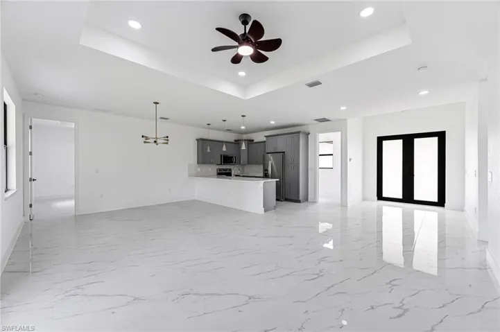 living room featuring french doors, a raised ceiling, and ceiling fan
