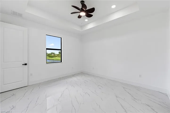Primary bedroom featuring a raised ceiling and ceiling fan