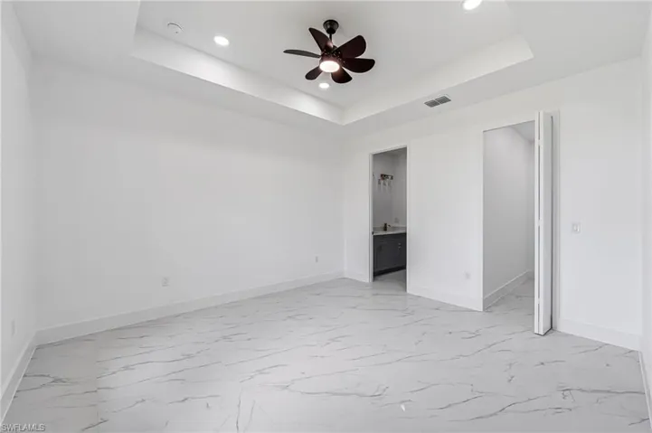 Primary bedroom featuring a raised ceiling and ceiling fan