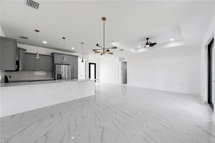 living room featuring a tray ceiling, plenty of natural light, and ceiling fan with notable chandelier