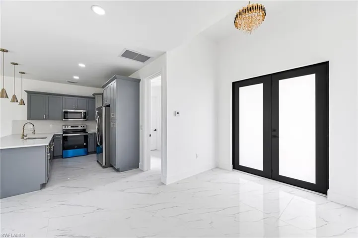 Kitchen with sink, stainless steel appliances, a notable chandelier, decorative light fixtures, and gray cabinets