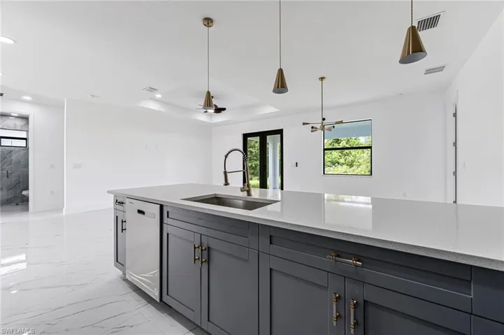 Kitchen featuring white dishwasher, gray cabinetry, light stone countertops, and sink