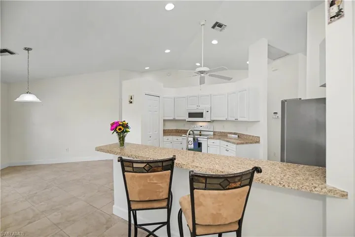 lbreakfast bar and breakfast area in sight under the hanging light with view of the backyard