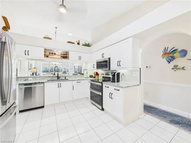 Kitchen with white cabinets, light stone countertops, and stainless steel appliances