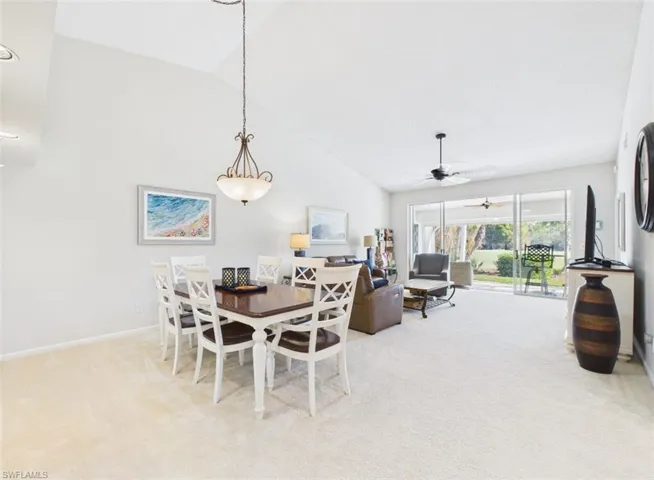 Dining area featuring vaulted ceiling, light carpet, and ceiling fan