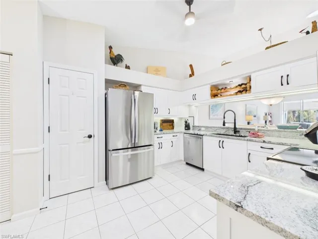 Kitchen with appliances with stainless steel finishes, white cabinets, light stone countertops, and light tile patterned floors