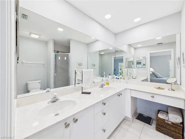 Ensuite bathroom featuring a shower stall, double vanity, light tile patterned flooring, and recessed lighting