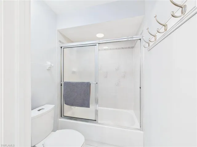 Full bathroom with toilet and shower / bath combination with glass door
