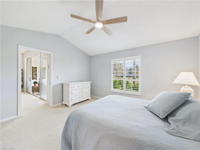 Bedroom with vaulted ceiling, a ceiling fan, and carpet floors