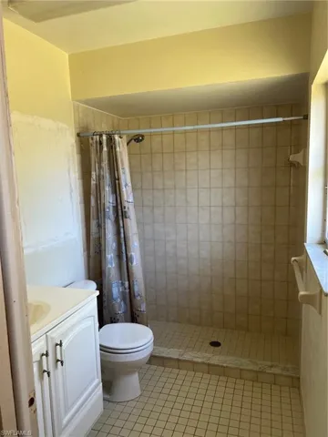 Bathroom with tile patterned floors, toilet, vanity, and a shower with shower curtain