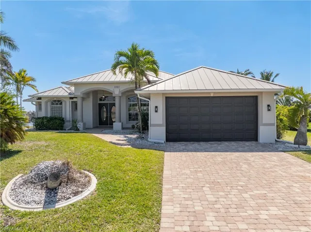 View of front of house with metal roof, decorative driveway, stucco siding, and french entry doors
