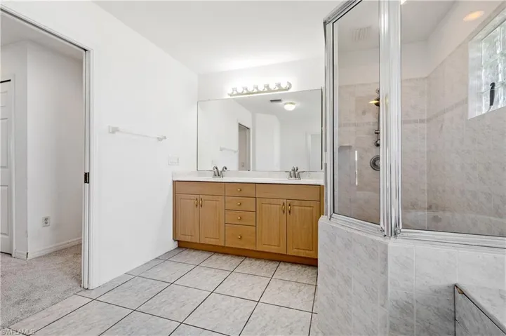 Primary Bathroom with double vanity, tiled walk in shower, and soaker tub