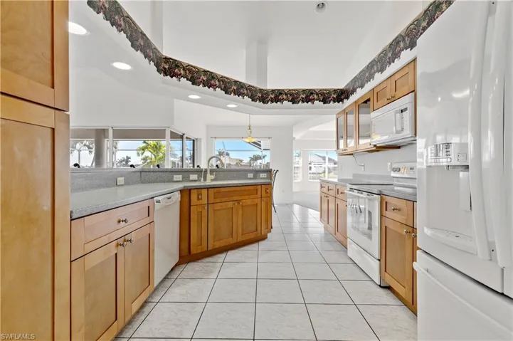 Kitchen with a peninsula, white appliances, recessed lighting, pendant lighting, and light tile patterned floors