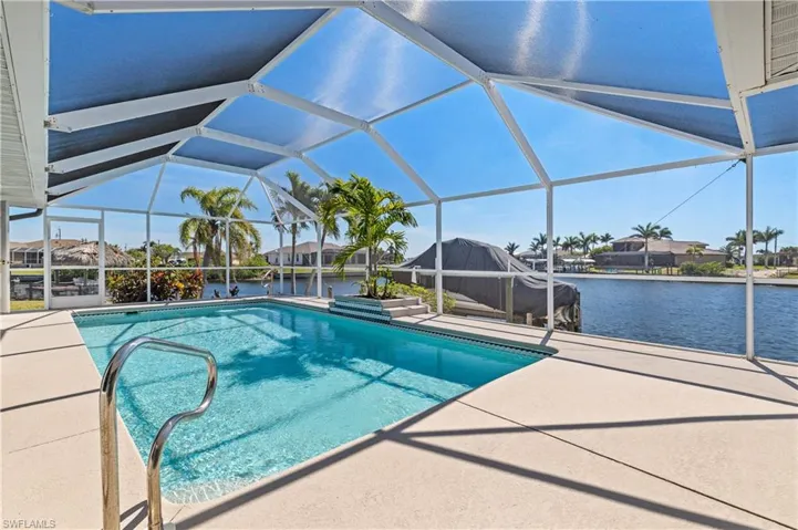 Pool featuring a water view, screened enclosure, and a patio