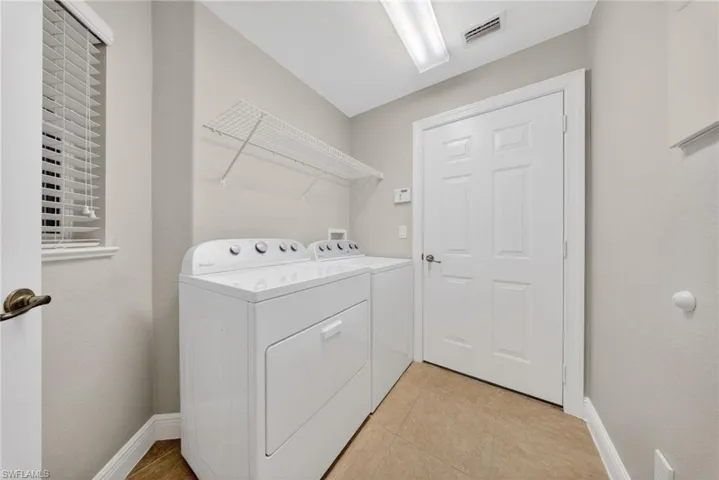 Laundry area featuring independent washer and dryer and light tile patterned flooring