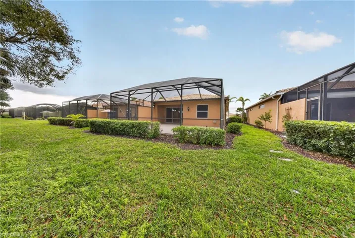 Back of property featuring glass enclosure, a sunroom, a lawn, and stucco siding