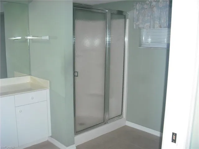 Bathroom featuring vanity, tile patterned floors, and a shower with door