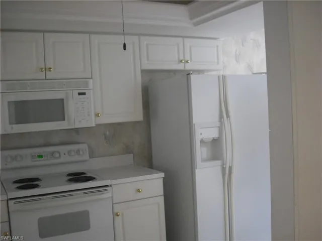 Kitchen featuring tasteful backsplash, white cabinetry, and white appliances