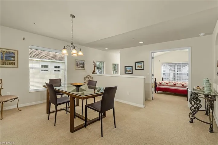Dining area with light colored carpet, a notable chandelier, and plenty of natural light