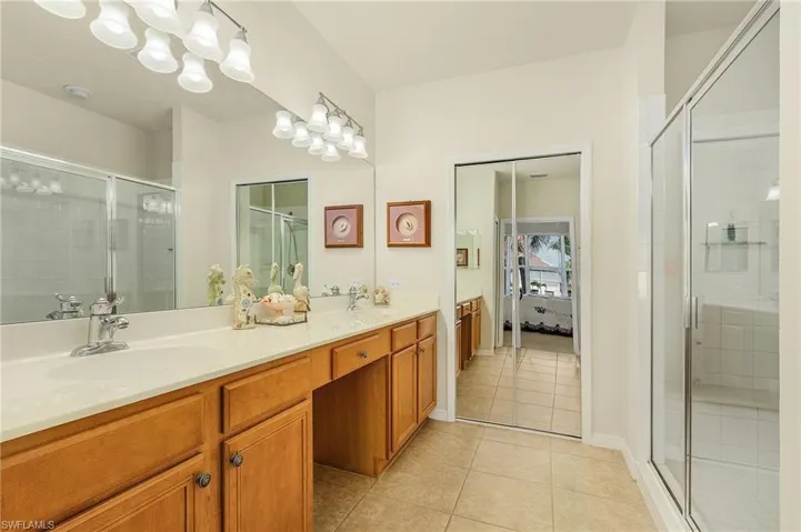 Bathroom with vanity, a shower with shower door, and tile patterned flooring