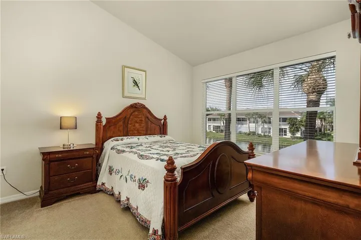 Bedroom featuring light carpet and vaulted ceiling
