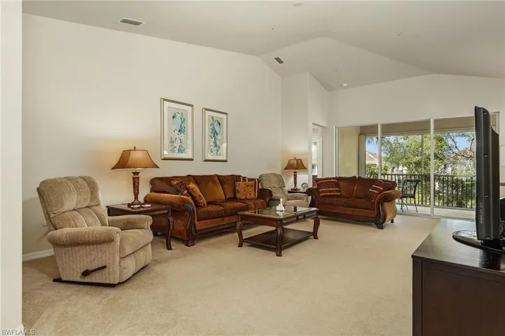 Carpeted living room featuring vaulted ceiling