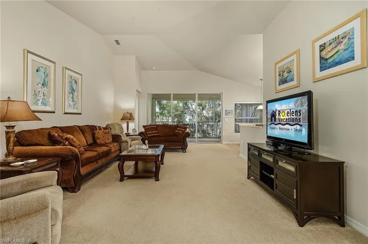 Living room with vaulted ceiling and light carpet