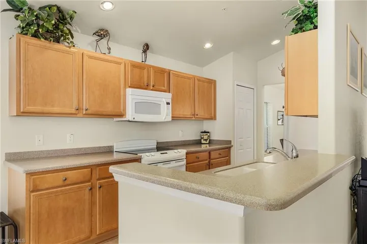 Kitchen with white appliances, sink, a breakfast bar, and kitchen peninsula